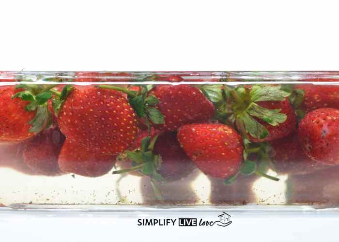 clear bowl of strawberries soaking in DIY fruit wash