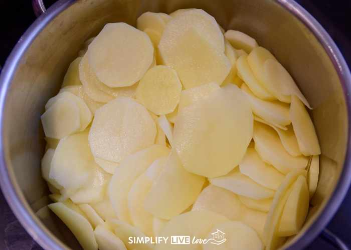 thinly sliced potatoes in silver pot