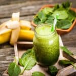 green smoothie with spinach and banana in glass jar with straw