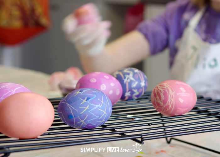 pink, purple, and orange dyed easter eggs with designs from white crayon on cooling rack