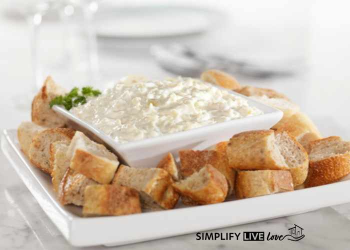 parmesan asiago spread on a white plate with crusty bread