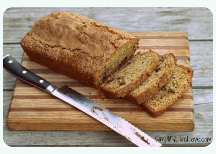 homemade zucchini bread with chocolate chips on a wooden cutting board with knife