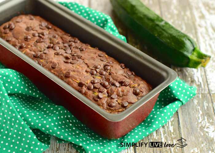zucchini bread with chocolate chips in a loaf pan on a green towel