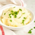 Creamy pepper jack mashed potatoes in white bowl with fresh garnish