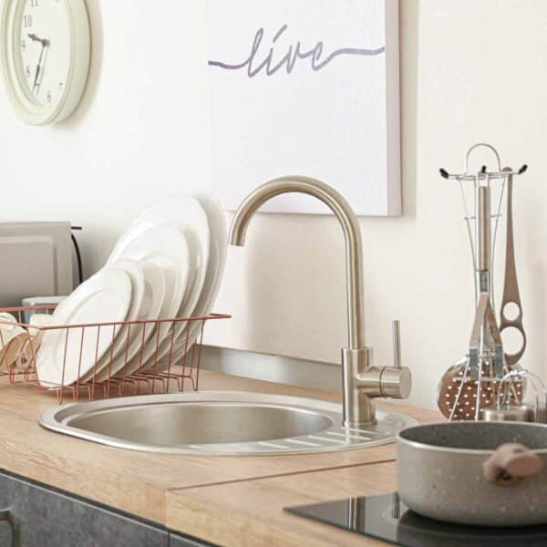 organized kitchen sink and counter with utensils elevated and clean dishes in rack