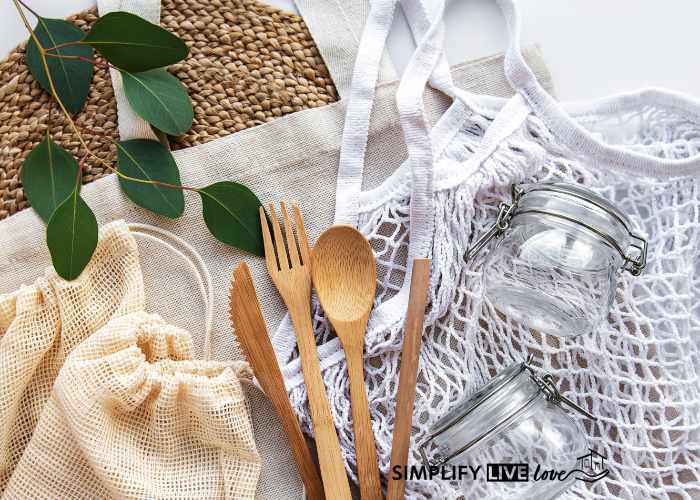 eco-friendly cloth bag, wooden utensils, glass jars, and greenery laying on table