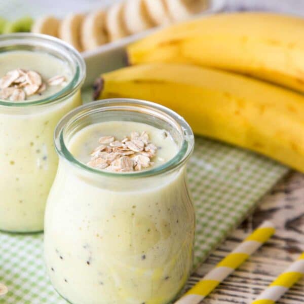 green shamrock shake smoothie in glass jars with bananas and kiwis in background