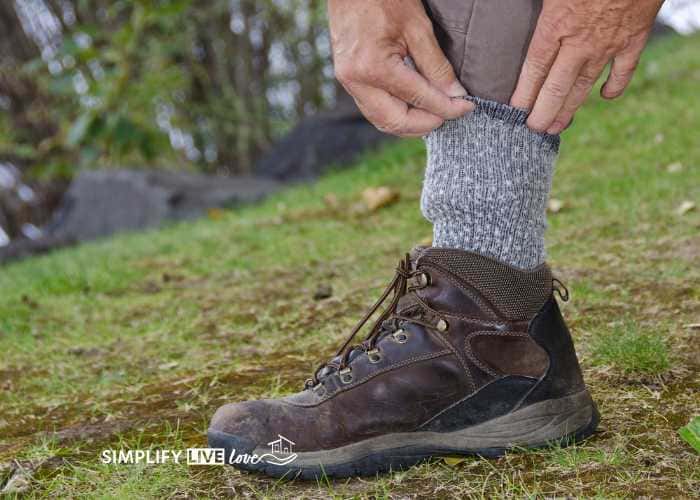 Man tucking pants into socks to prevent tick bites while hiking