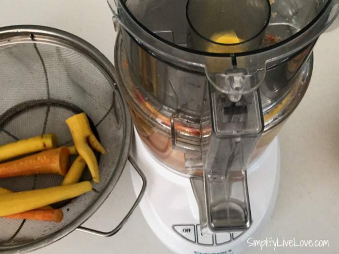 Food processor with carrots inside to prepare them for freezing