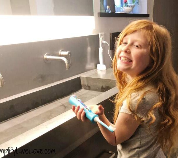red headed girl brushing her teeth with natural toothpaste for kids