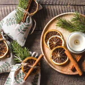 dried orange slices next to candle and decorating small potpurri gift bags with rosemary and cinnamon