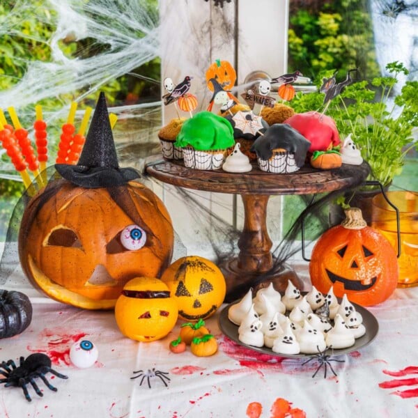 pumpkins, cupcakes, cookies, in a Halloween dinner party decor on a table