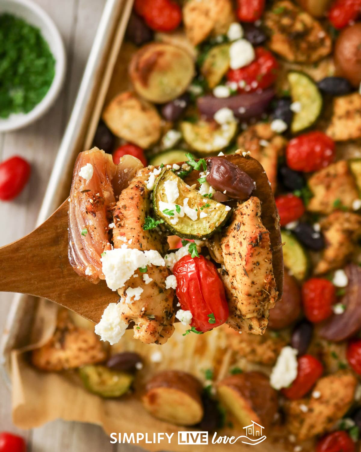 bit of chicken, zucchini, feta cheese, olive on a wooden spoon