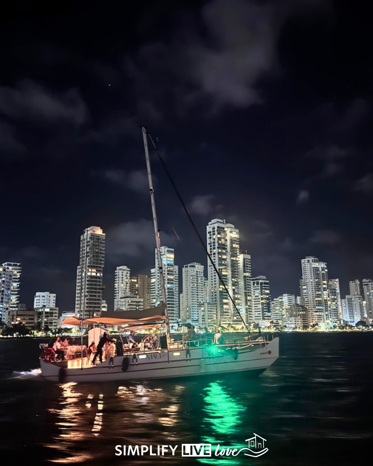 sail boat at night in cartagena with the city lit up in the background