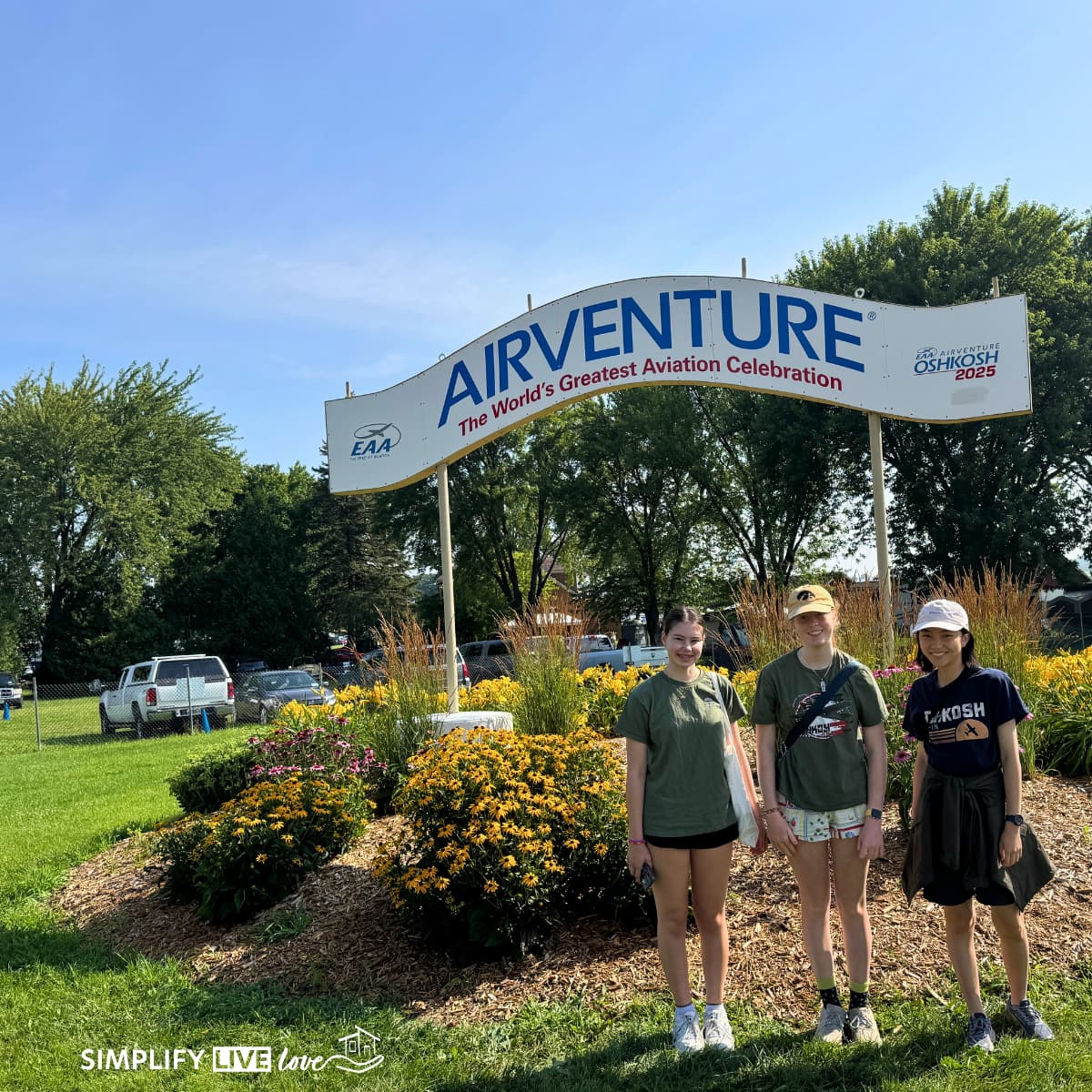 3 girls standing next to the EAA AirVenture sign at Oshkosh.