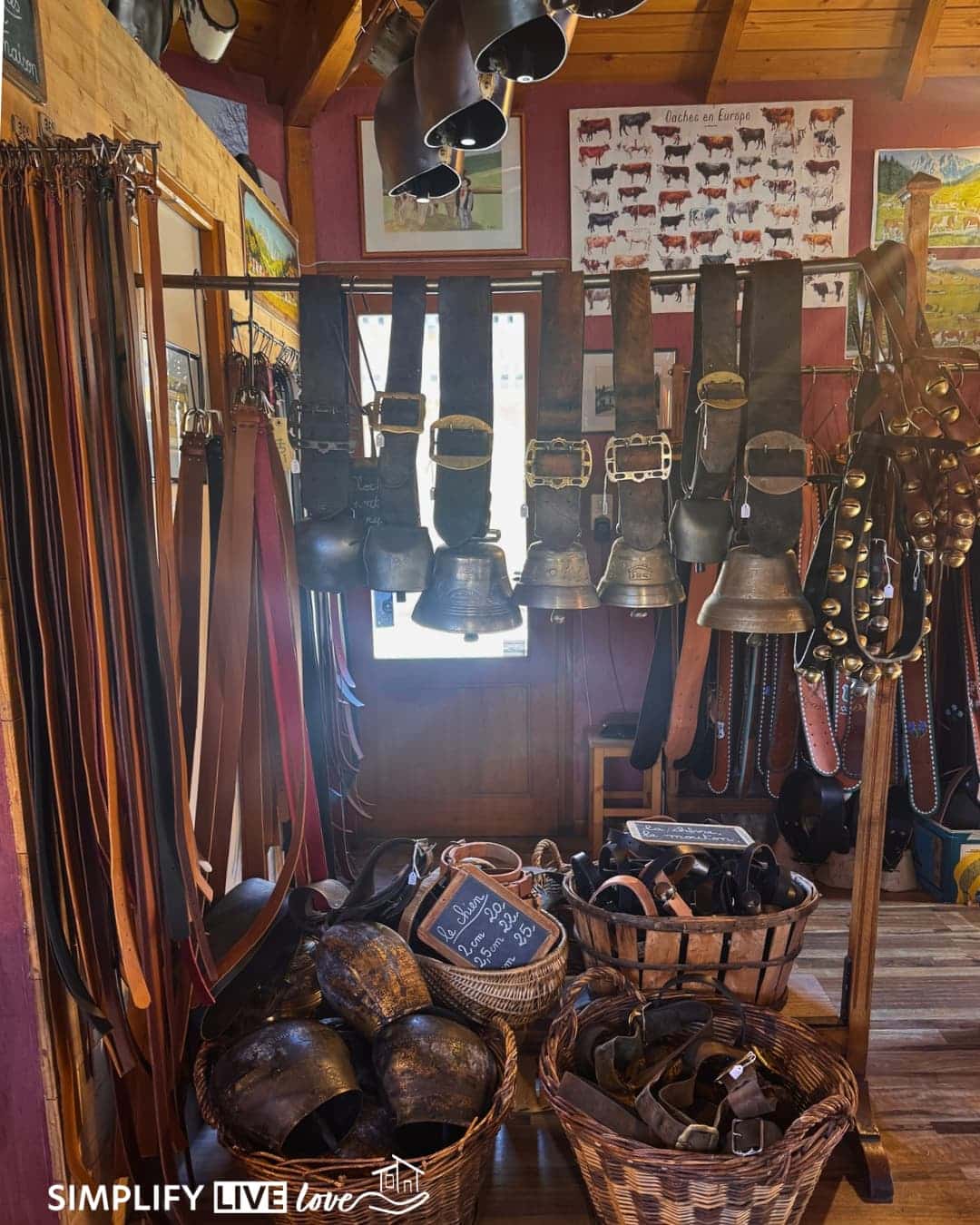 hand forged large bells haning from the ceiling, lots of leather belts hanging from the wall, and baskets of bells on the floor at Fonderie Obertino Bell Foundry